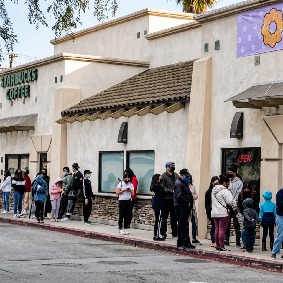 People line up outside a Starbucks Coffee storefront beneath a colorful Mochinut banner.